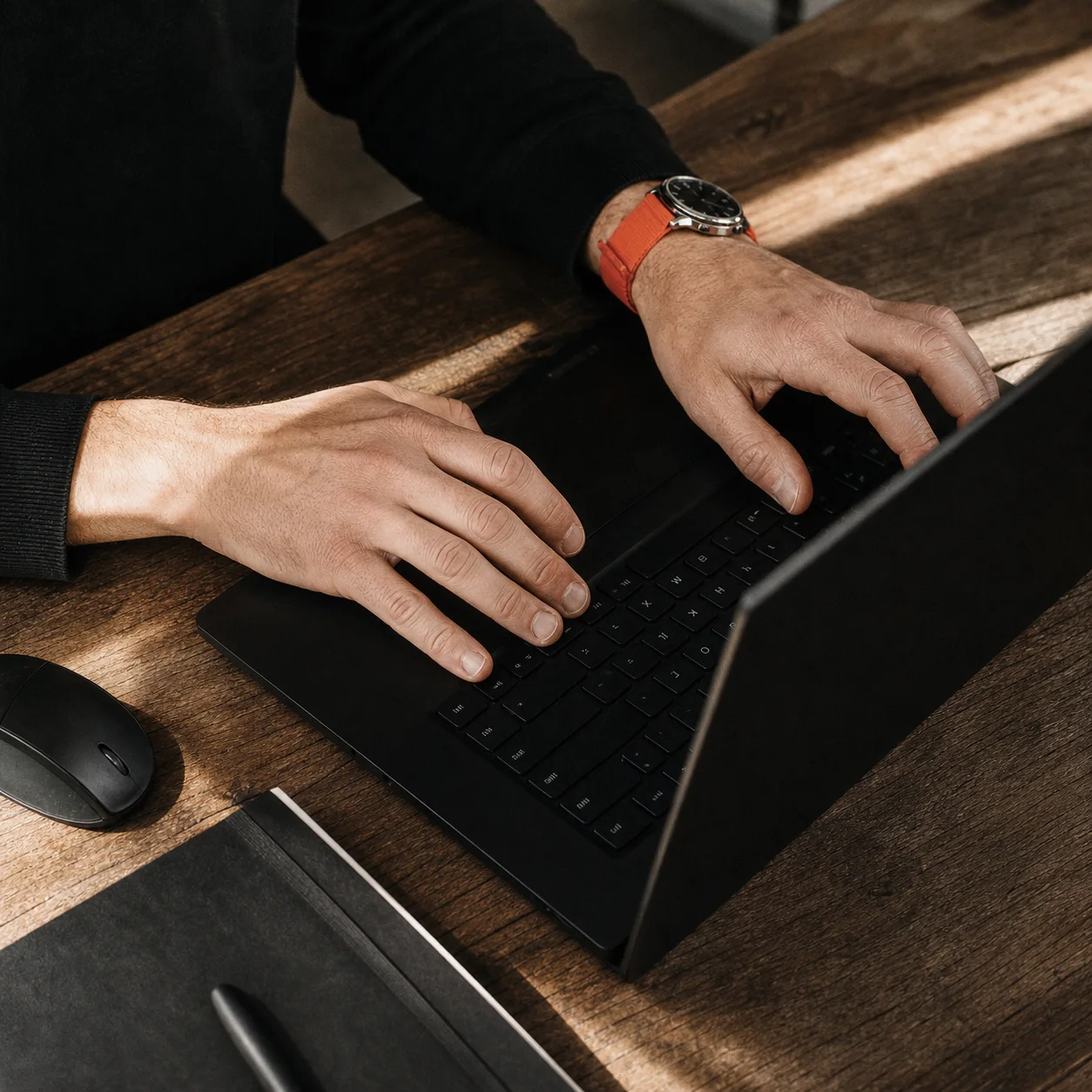 Hands working on a digital project at a black laptop in Mousehold Studio